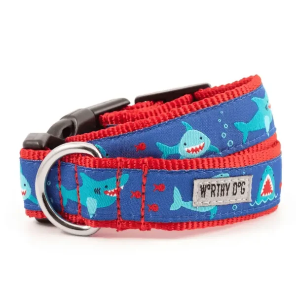 A dog collar featuring a blue fabric with shark illustrations and red accents.
