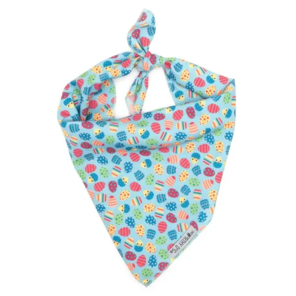 A colorful dog bandana featuring a pattern of egg shapes and designs, tied in a knot at the top.