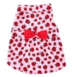 A pink dog dress featuring a pattern of red ladybugs and a red bow.