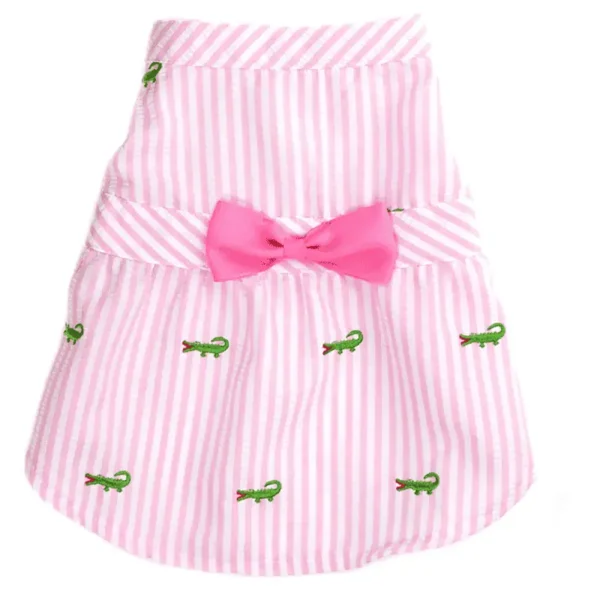 A pink striped dog dress with green alligator embroidery and a pink bow.