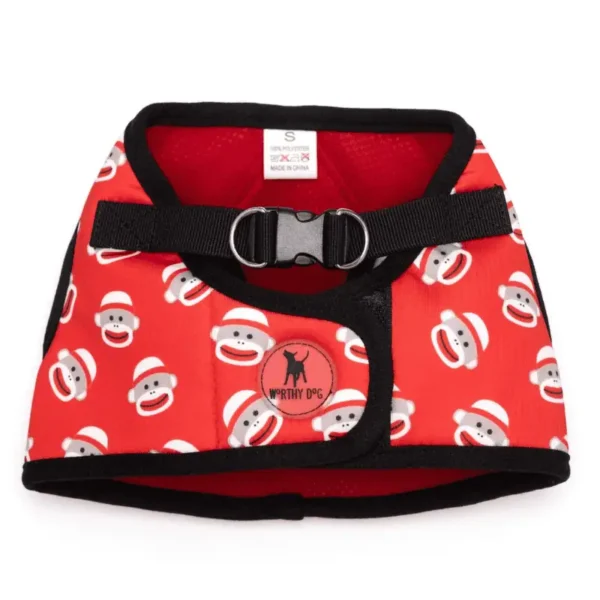 A red dog harness vest featuring a repeating pattern of sock monkey faces wearing hats.