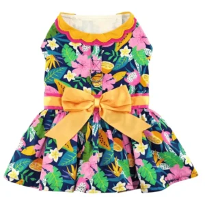 A colorful dog dress with a floral pattern, featuring pink flowers, green leaves, and a yellow bow at the waist.