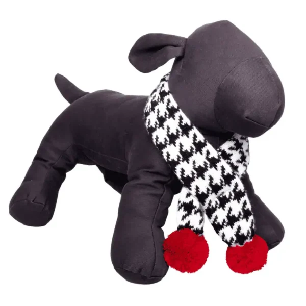 A black plush dog mannequin wearing a black and white houndstooth scarf with red pom-poms.