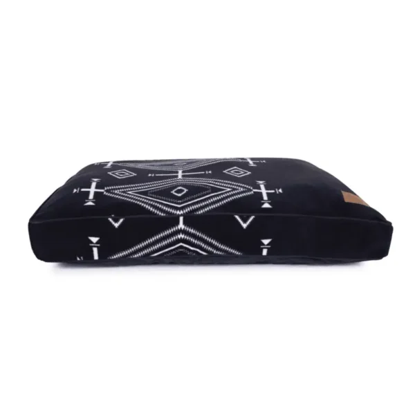 A black pet bed with white geometric tribal patterns.