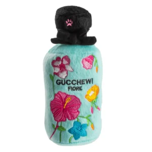 Plush turquoise Gucchewi Fiore Pawfum dog toy shaped like a perfume bottle with black cap, hot pink paw, pink, yellow, and blue embroidered flowers, and black embroidered “Gucchewi Fiore” text. Soft squeaky toy for stylish pups