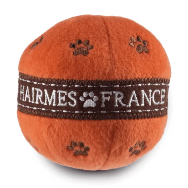 Orange plush ball dog toy with brown paw prints and white HAIRMES FRANCE label