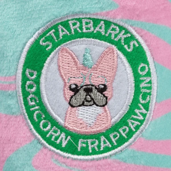 Close-up of ‘Starbarks Dogicorn Frapawccino’ label on plush cup with vibrant color swirls