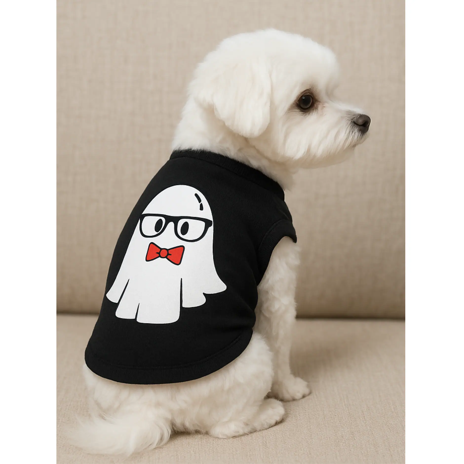 A white Maltese dog sitting wearing a black tank with a white ghost wearing glasses and a red bowtie