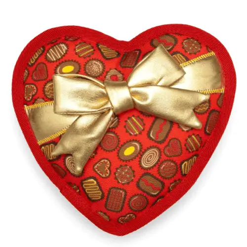 A red heart-shaped dog toy wrapped with a gold bow with mini candy chocolates design all over.